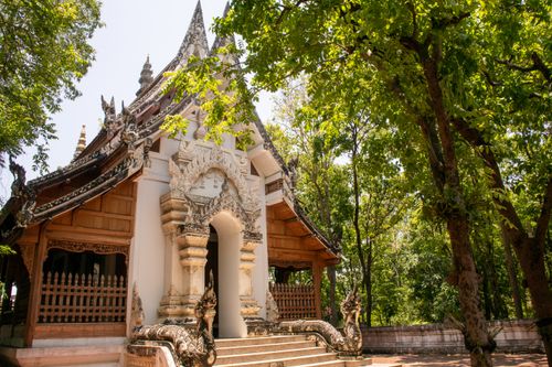 Free A beautiful Buddhist temple surrounded by lush green trees, showcasing intricate architectural details. Stock Photo