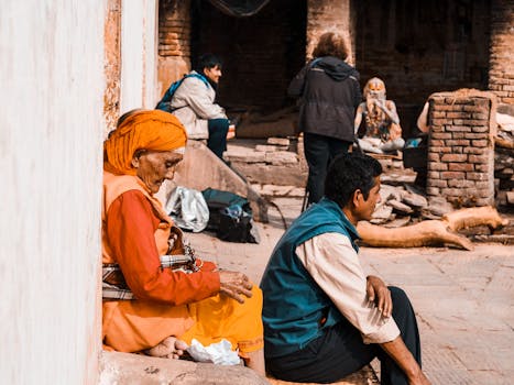 A group of diverse individuals sitting and talking near ancient brick ruins in an outdoor setting.