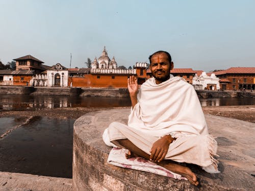 Man in White Robe Sitting on Concrete Surface 