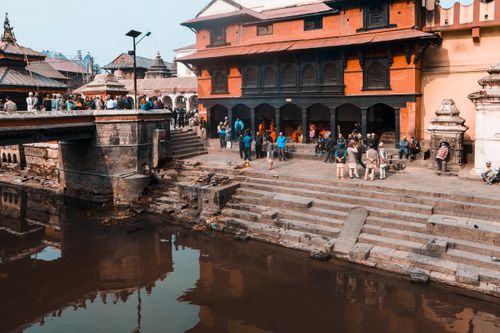 Free Scenic view of Pashupatinath Temple by the Bagmati River with bustling crowd and historic architecture. Stock Photo