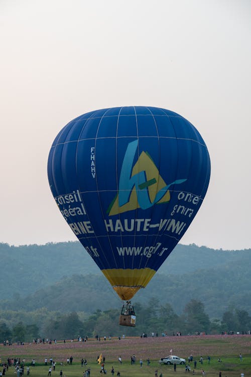 Blue Hot Air Balloon Flying Over the Field