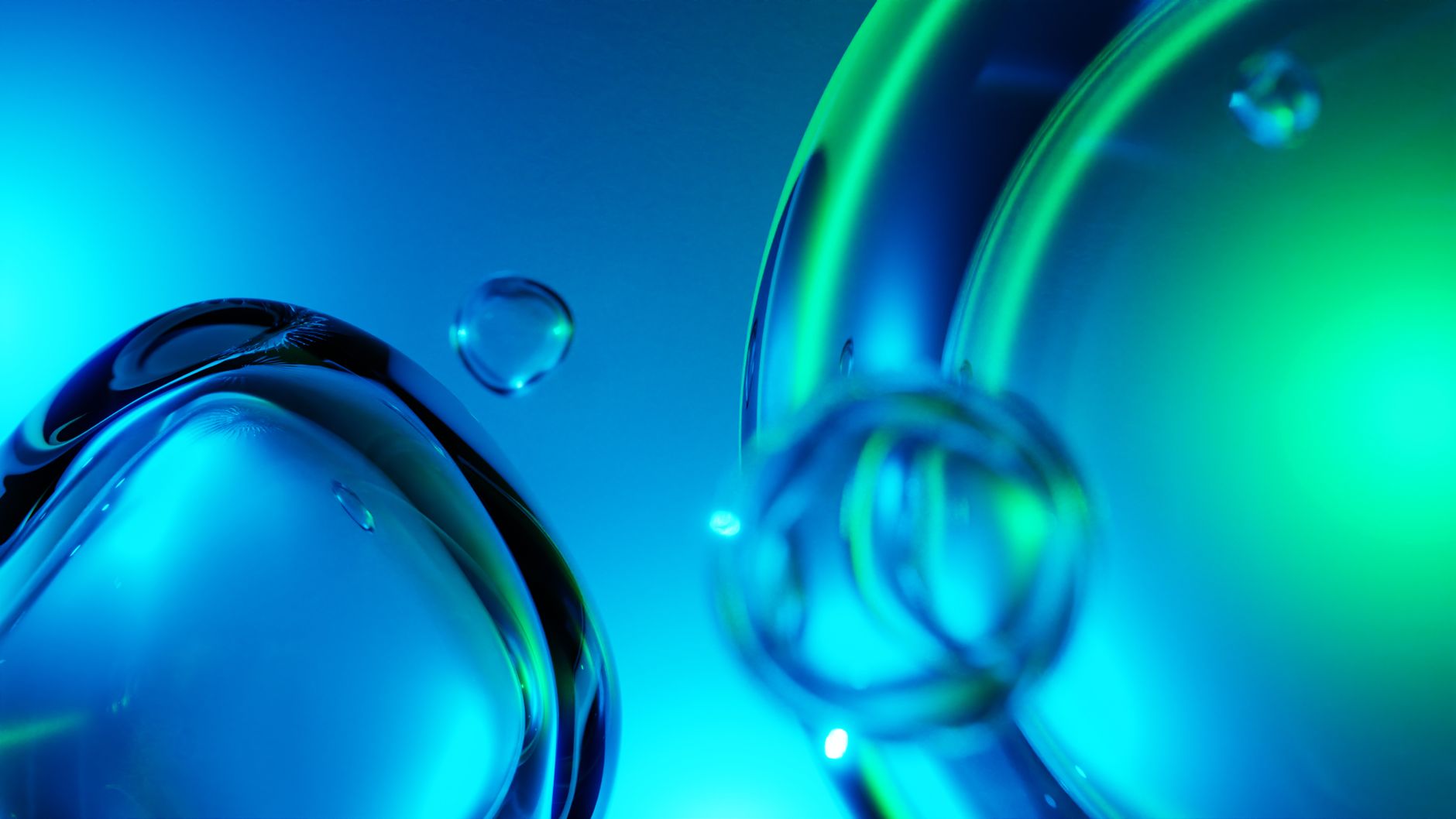 Close-up of liquid bubbles displaying vibrant blue and green hues on a smooth background.