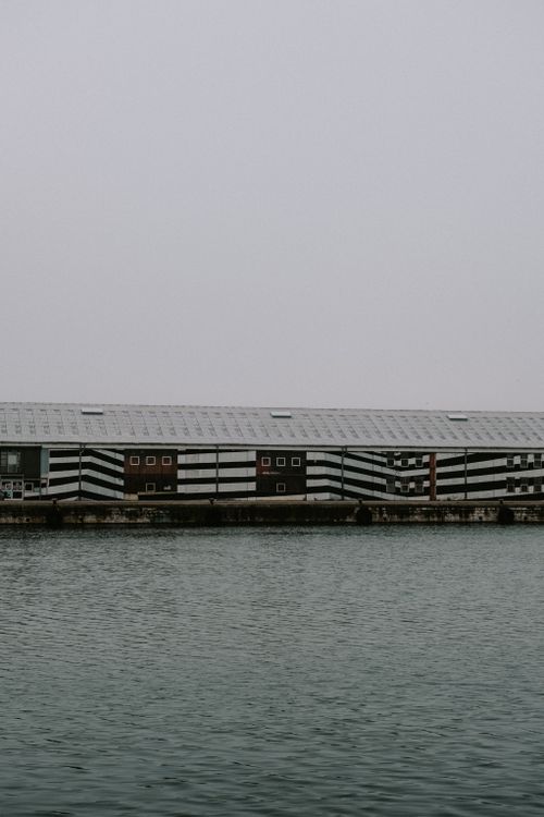 Free Striped industrial buildings line the harbor under an overcast sky. Stock Photo