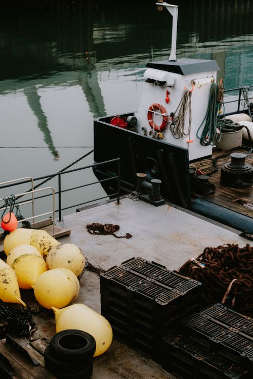 Free Fishing boat moored at the dock with yellow buoys and marine equipment visible. Stock Photo