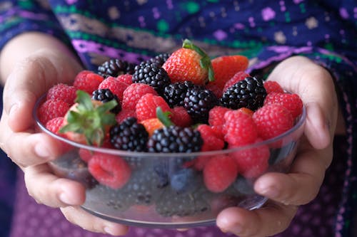 Person Holding Mixed Berries on a Glass Bowl