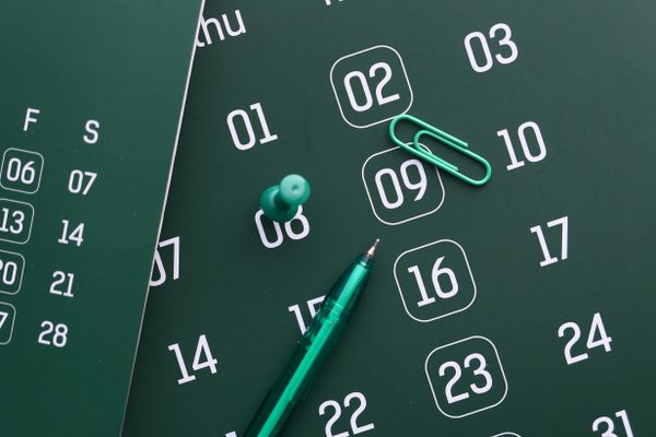Calendar with a pushpin, paper clip, and pen marking a moving date to plan how far in advance to book movers