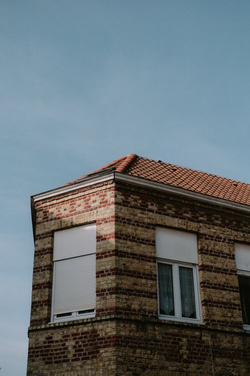 Free Corner of a brick building with a tiled roof against a blue sky. Stock Photo