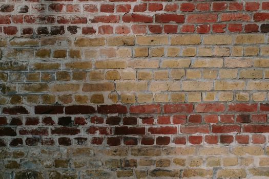 Detailed view of a rustic red and yellow brick wall, showcasing aged texture.