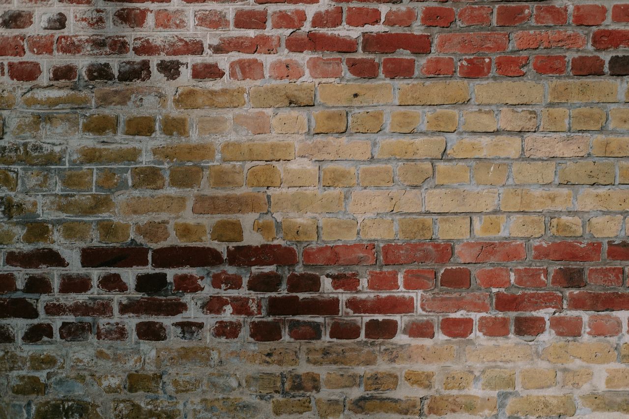 detailed view of a rustic red and yellow brick wall showcasing aged te