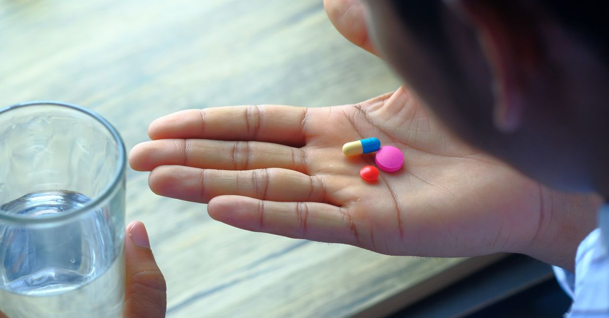 Novo Nordisk wins EU nod for oral Wegovy pill as US cyclospora outbreak spreads A hand holding a variety of pills alongside a glass of water, emphasizing health and medication.