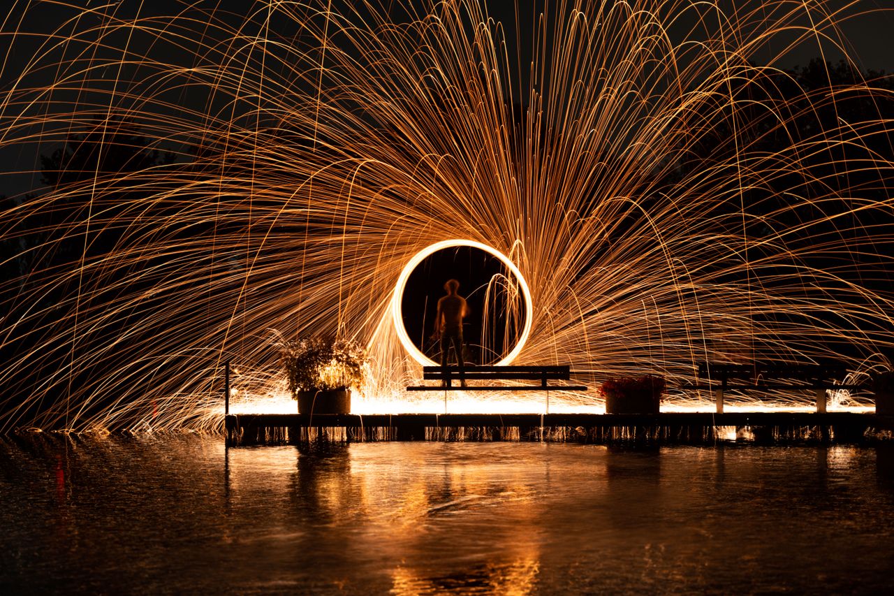 man performing steel wool spinning creating stunning light trails at n