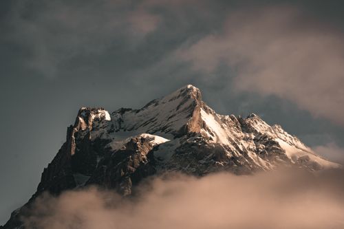Free A stunning snow-covered mountain peak rises through clouds, exuding a majestic and mysterious aura. Stock Photo