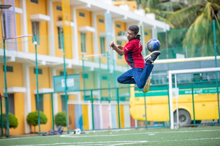 Young Student In School Uniform Playing Soccer On School Field