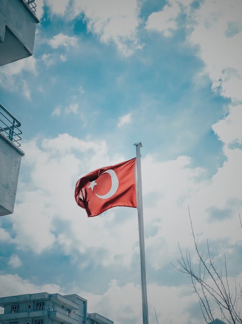 Red and White Flag on Pole Under Blue Sky