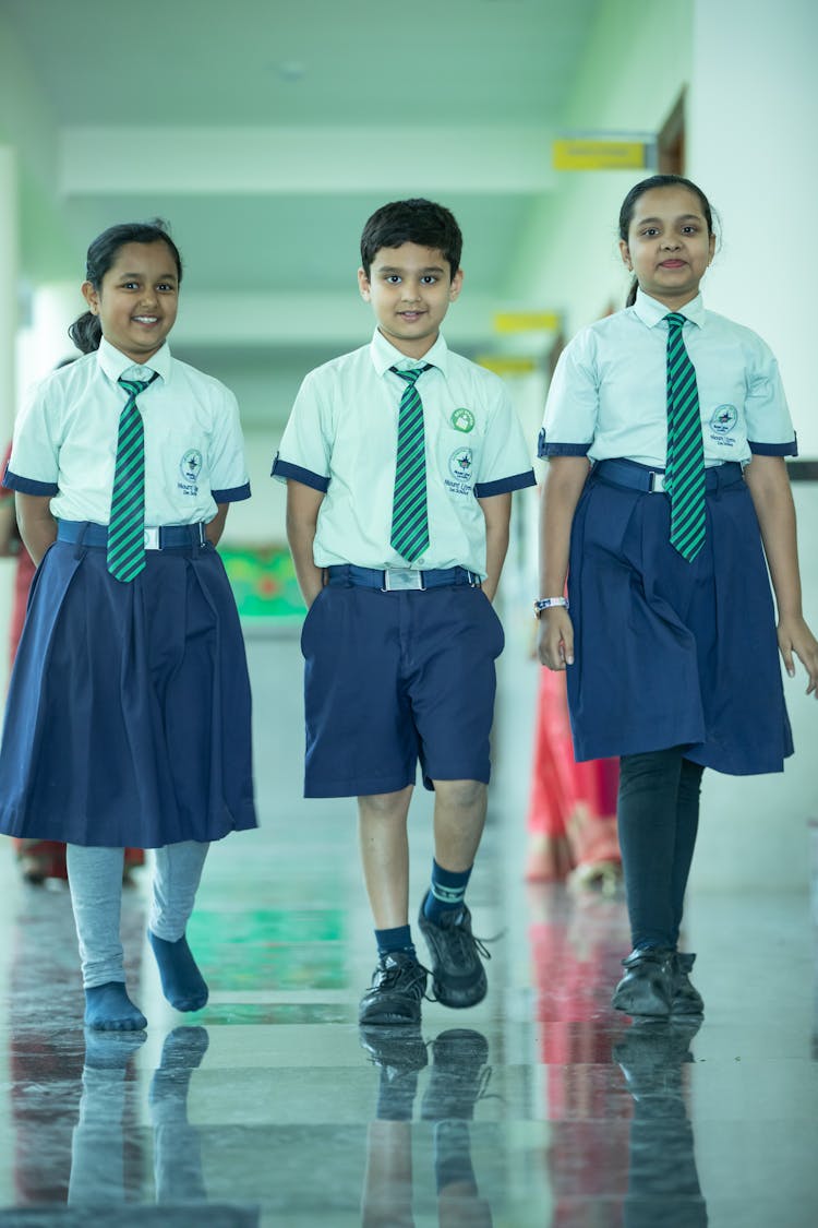 Boy And Two Girls Wearing School Uniform Walking Together