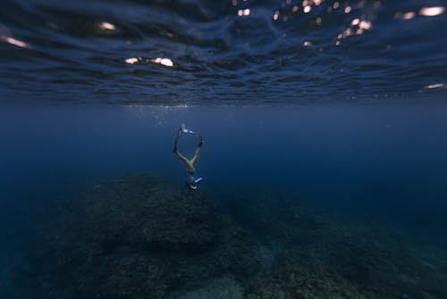 Free Person Diving and Swimming Down Towards Sea Bottom Stock Photo