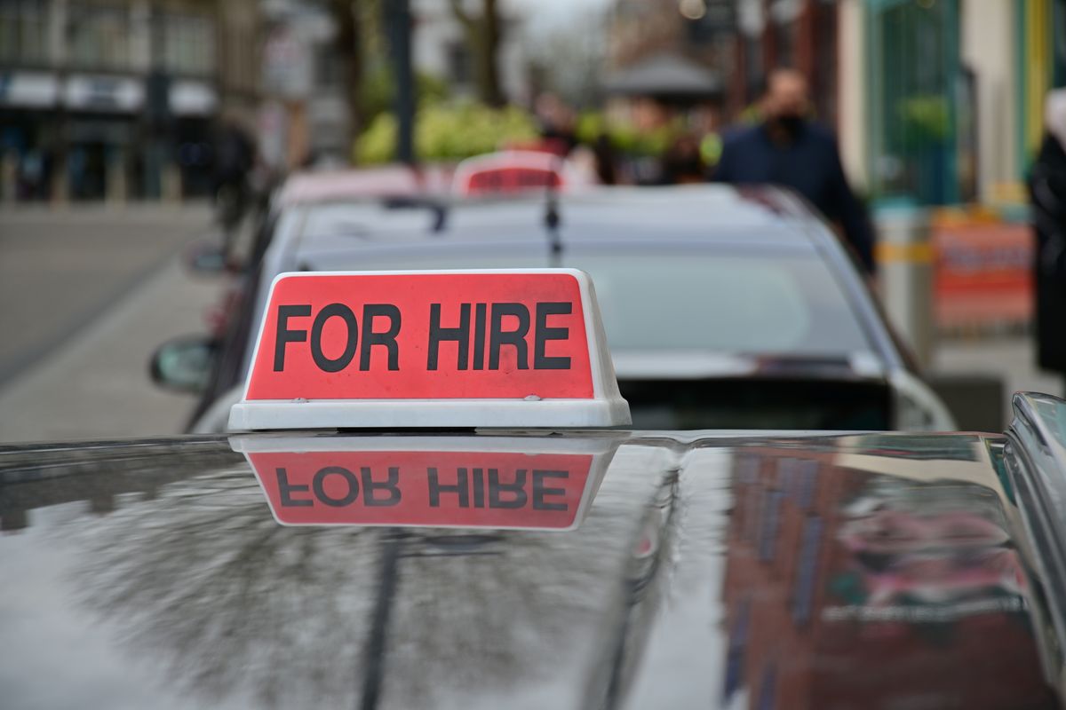 A 'For Hire' sign on the roof of a taxi parked on a UK street