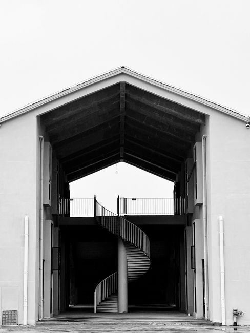 Dramatic monochrome image of a spiral staircase inside an open-structured building.