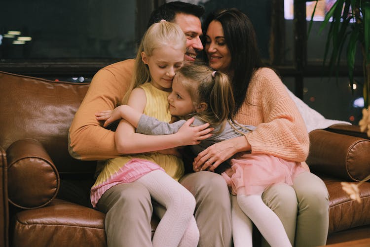 A Happy Family Sitting On A Couch While Hugging Each Other