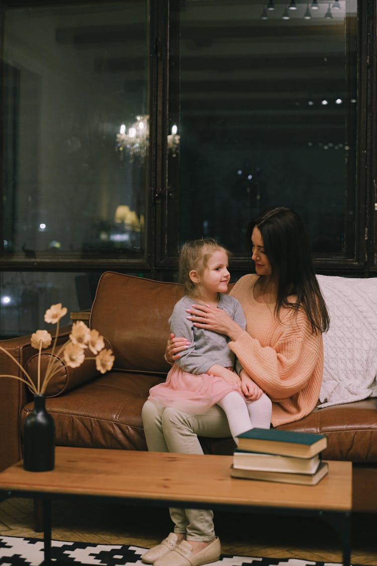 A Little Girl Sitting On Her Mother's Lap