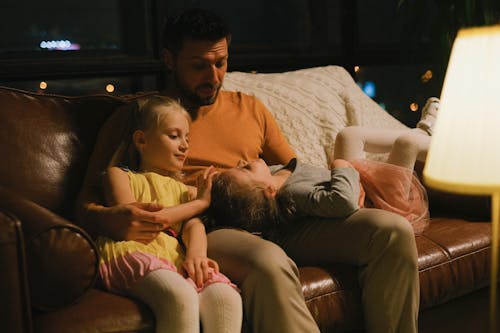 Free A Man Sitting with his Daughters on a Couch Stock Photo