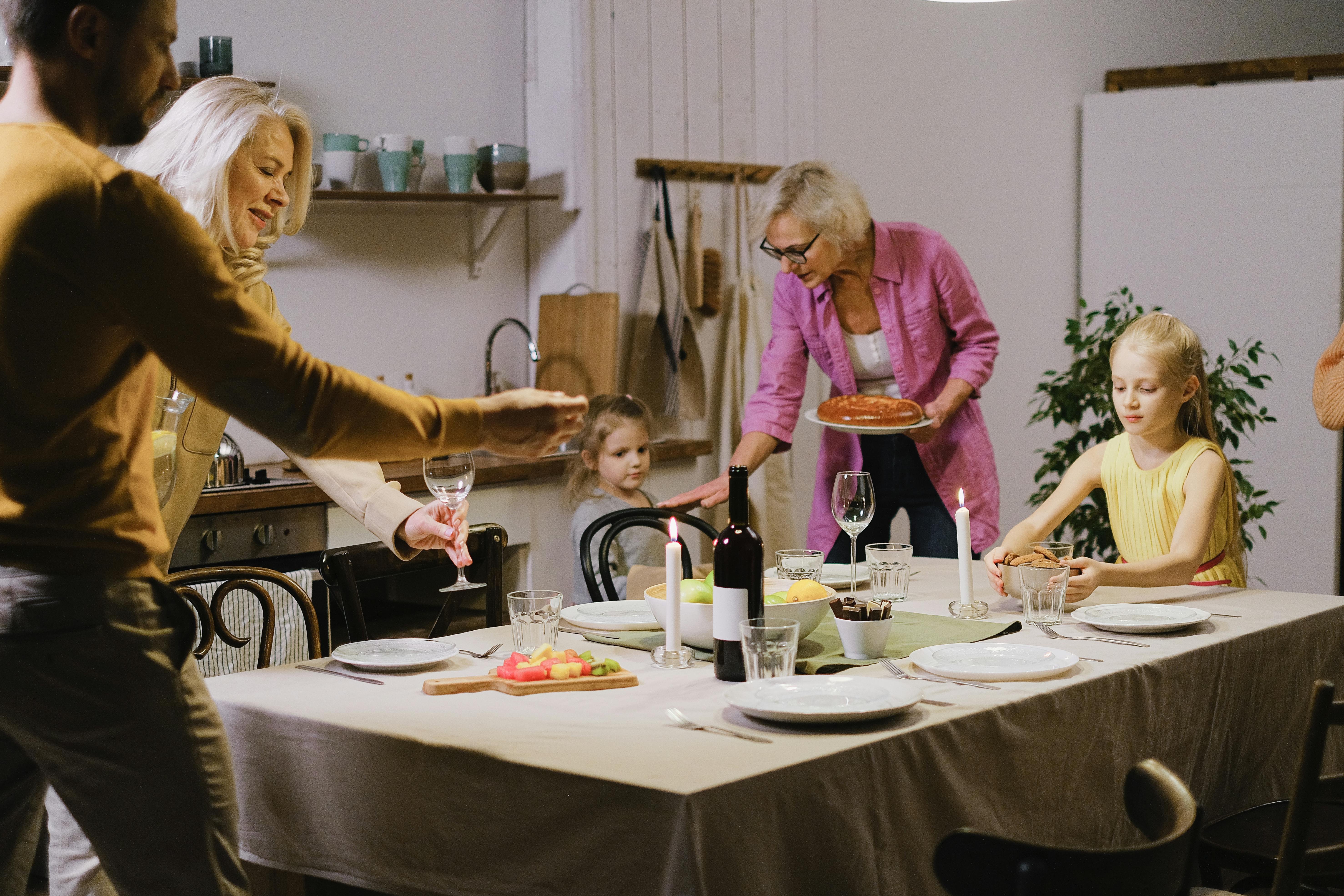A warm family gathering indoors with multi-generational members enjoying dinner preparation.