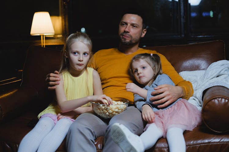 Man Sitting On Sofa With Two Girls