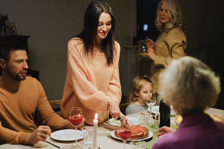 A Woman Slicing A Pie At A Dining Table