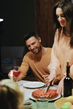 A family enjoying a cozy dinner with wine and homemade bread indoors.