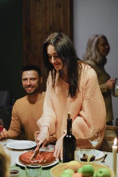 Woman slicing pie at a cozy dinner gathering, creating a welcoming atmosphere.