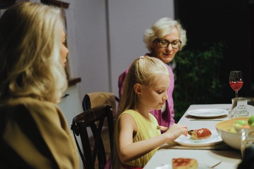 A warm family dinner with three generations enjoying a meal together indoors.
