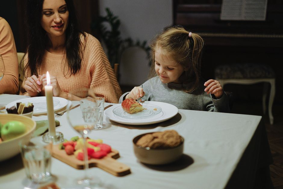 Photo by Anna Shvets on Pexels A young girl enjoys dessert at a family dinner table, creating a cozy home atmosphere. - Photo by Anna Shvets on Pexels