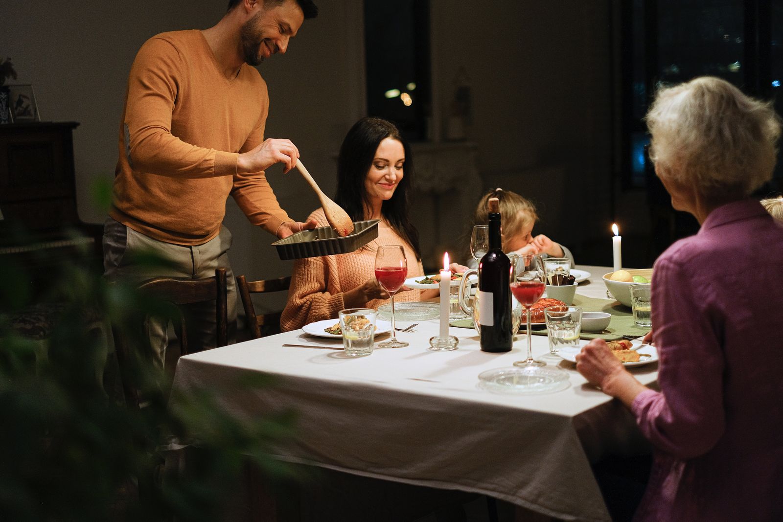 A family serving a warm candlelit dinner around the kitchen table — photo by Anna Shvets on Pexels