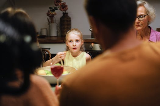 A young girl at a cozy family dinner table indoors, surrounded by relatives.