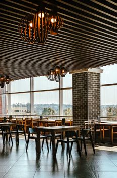 Sleek restaurant interior in Bengaluru, featuring wooden chairs and large windows overlooking the city.