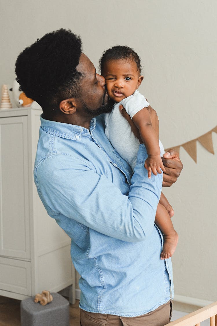 A Father Kissing A Baby On The Cheek