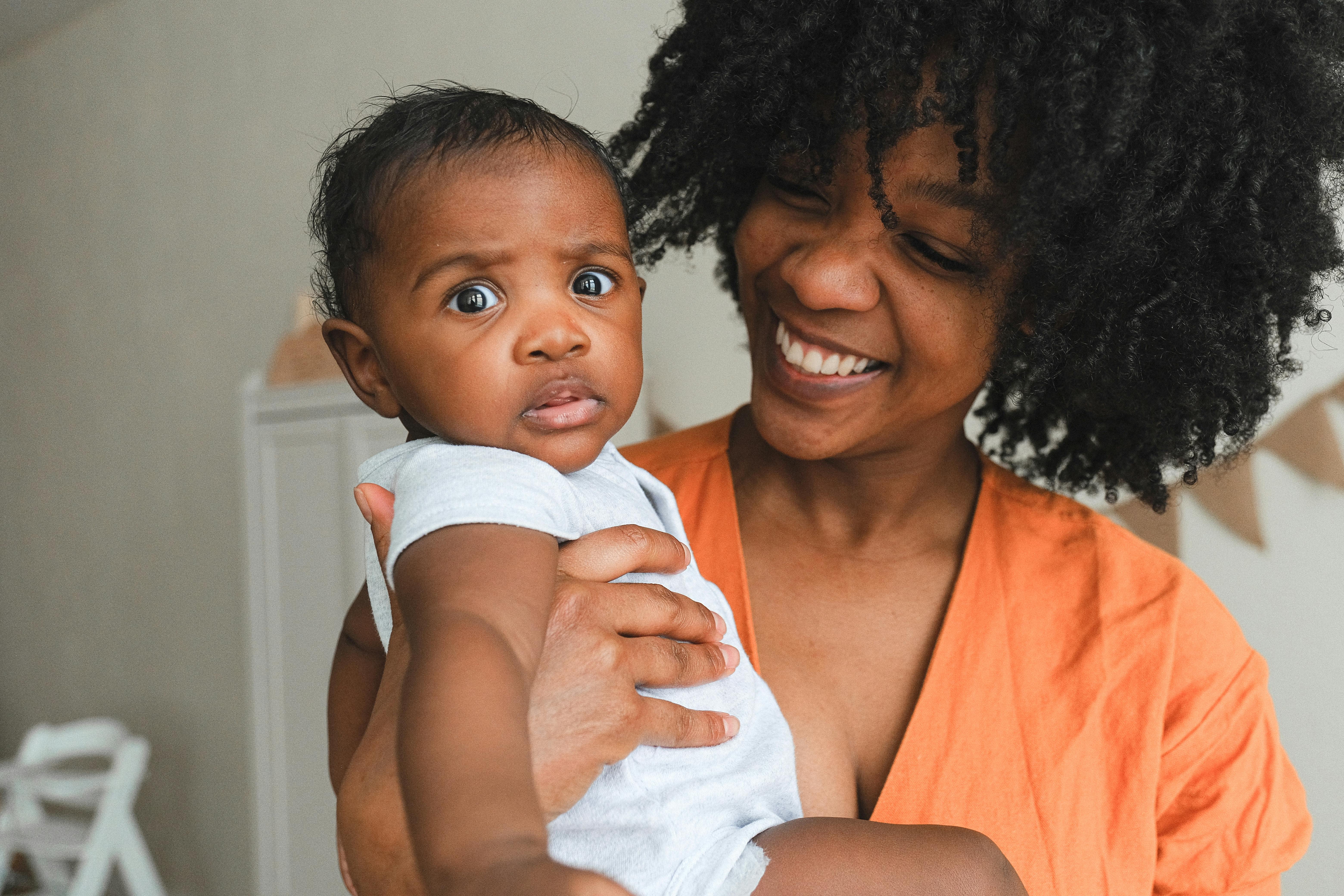 Happy African American mother holding her baby, capturing a warm family moment.