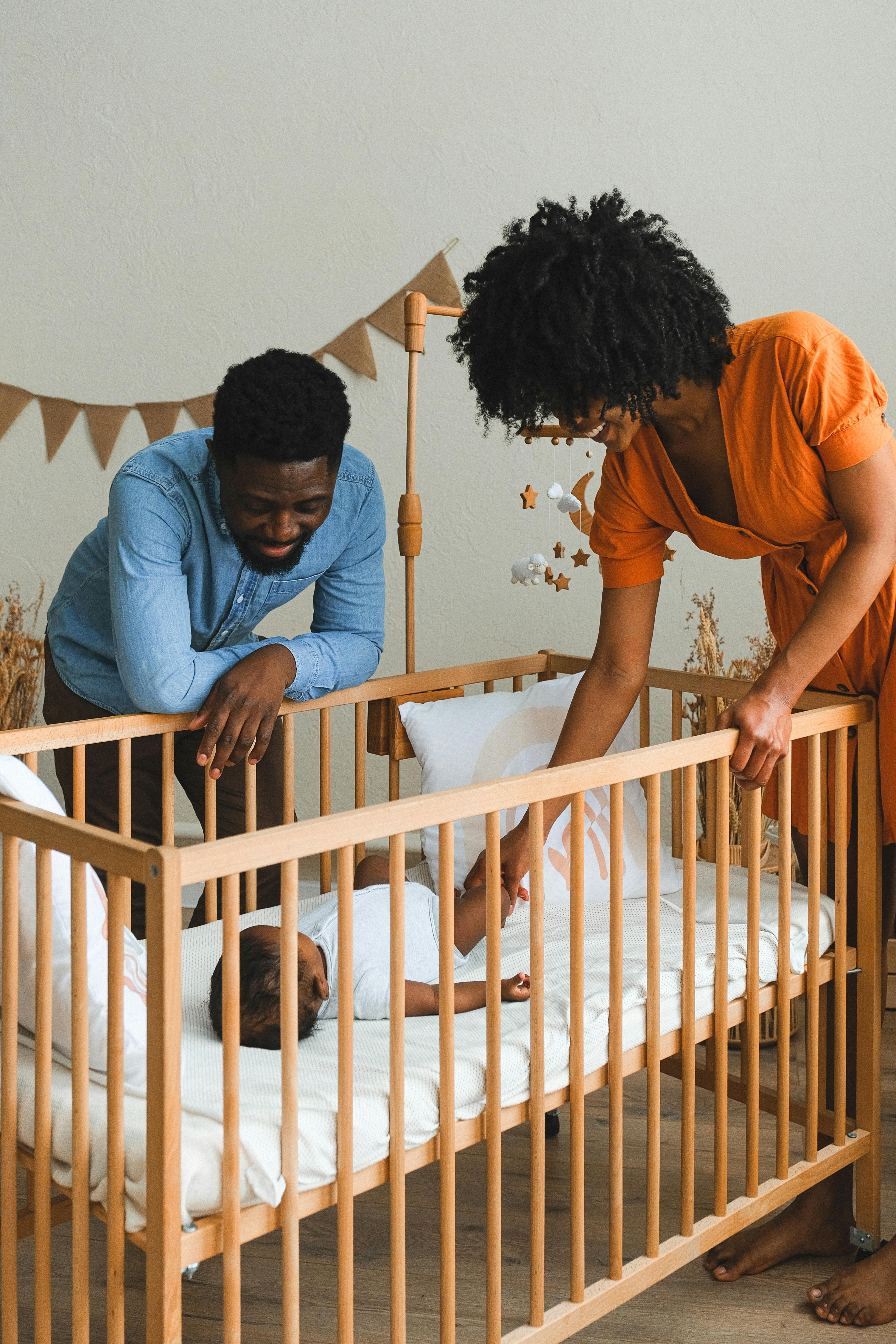 couple watching baby lying in crib