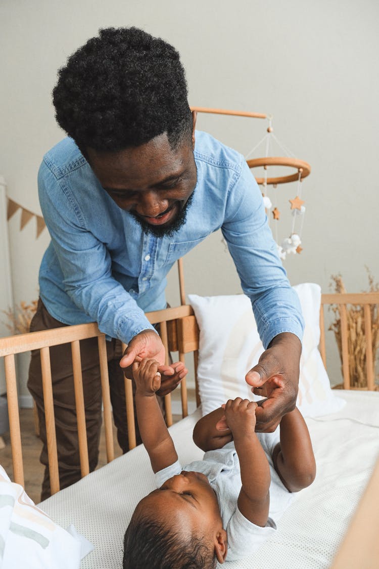 Father Playing With A Child On A Crib