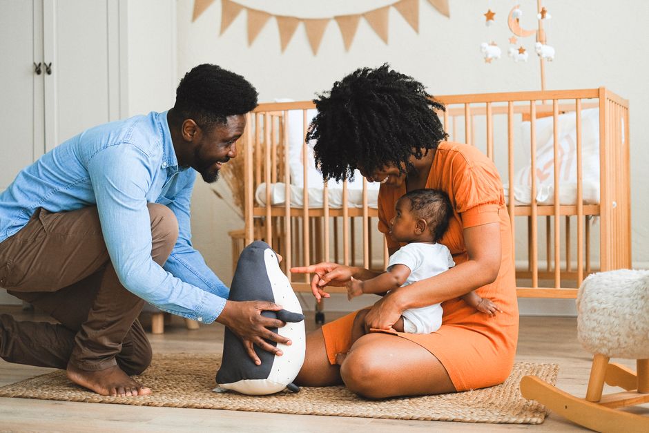 What Safety Research Reveals About Cribs, Monitors, and Sleep Gear Cheerful parents bonding with baby in modern nursery, experiencing precious moments.