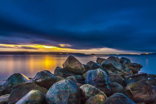Beautiful sunset over rocky coastline with calm sea and dramatic sky.