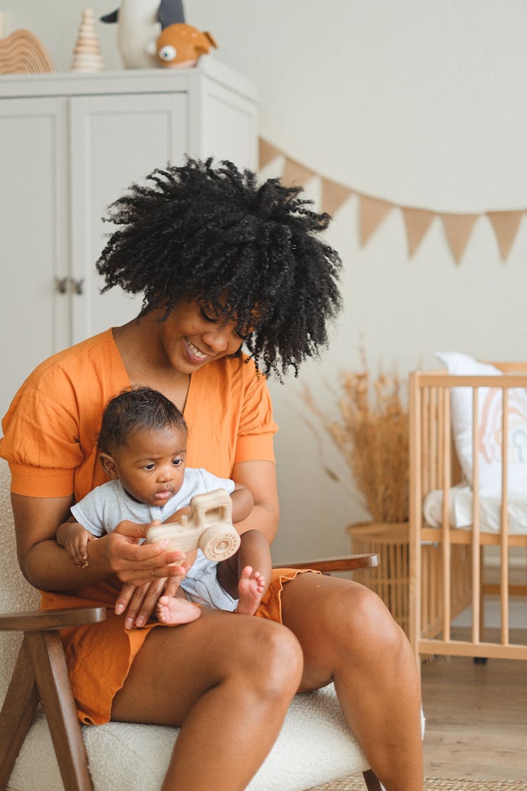 An Afro-Haired Woman Carrying A Baby