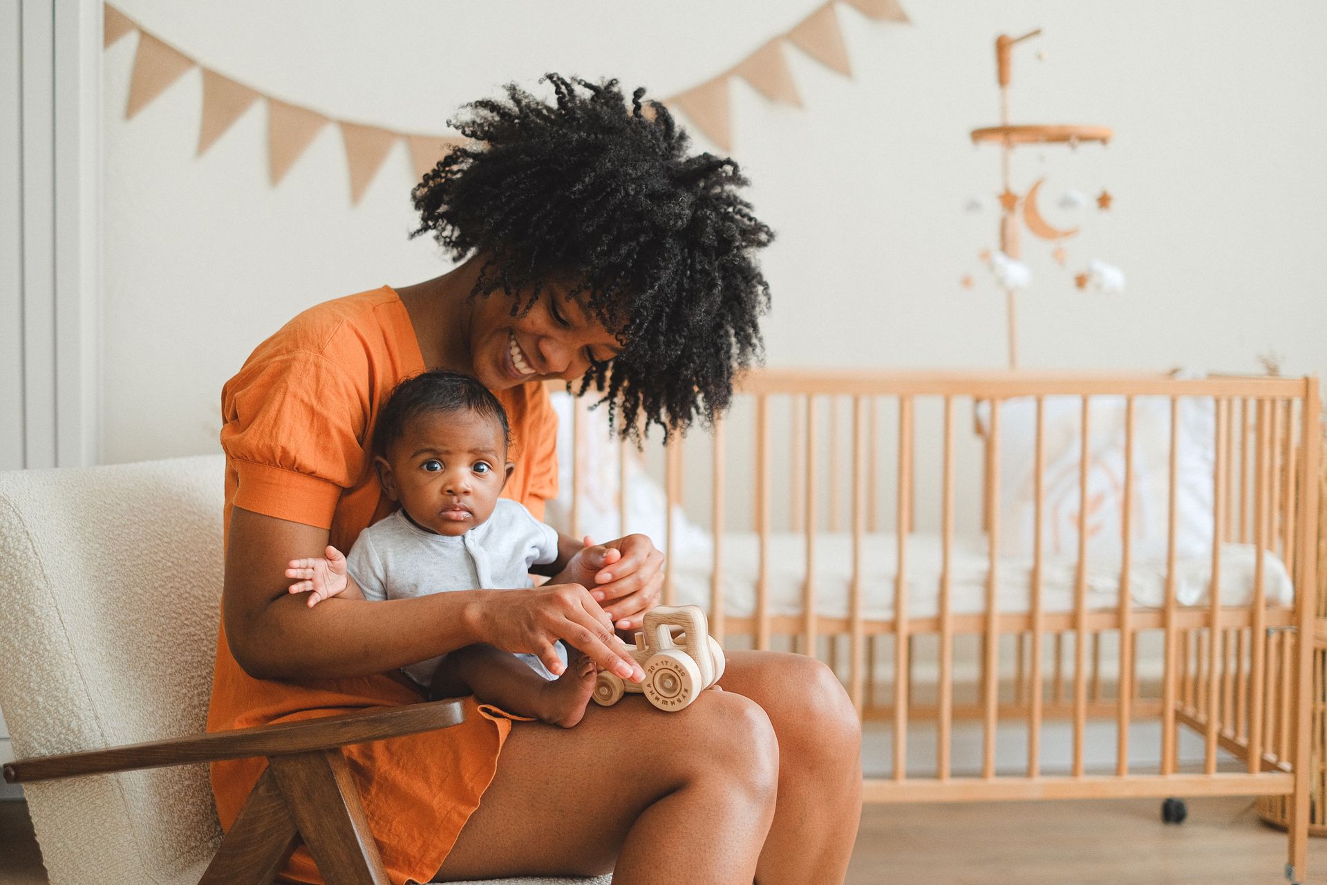 Woman Holding a Baby While Sitting on a Chair