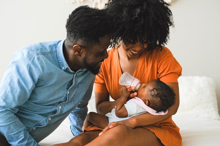 Woman Feeding A Baby Beside A Man