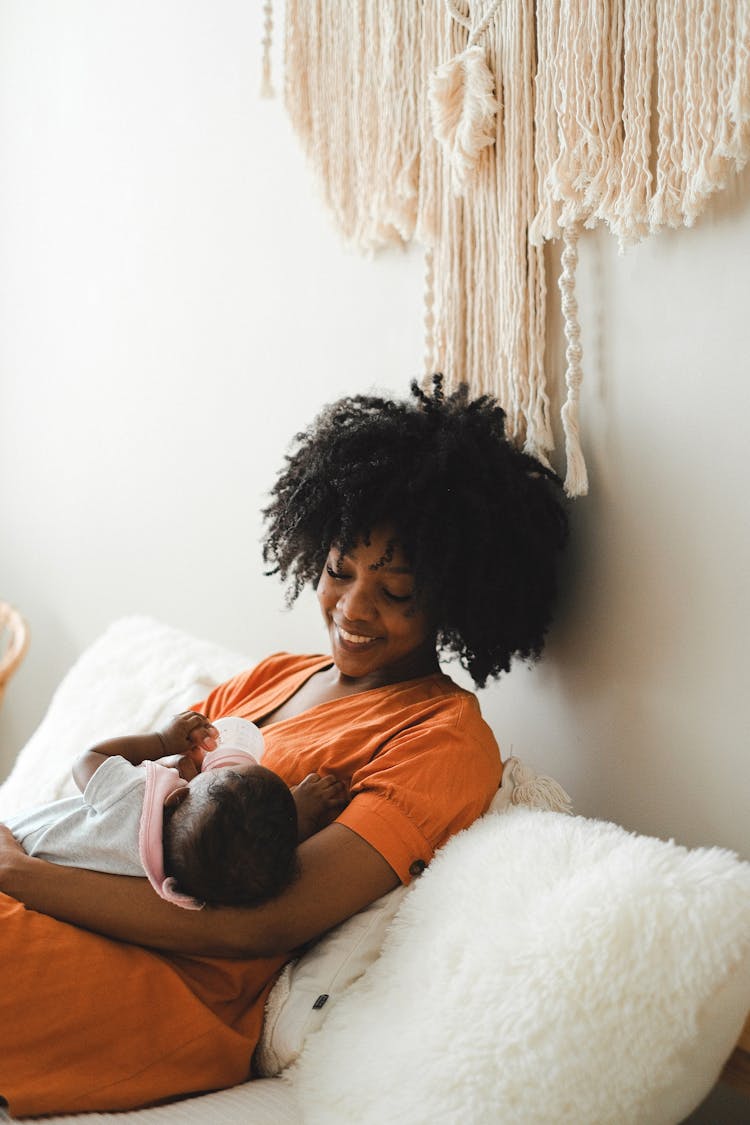 Woman With Afro Hair Feeding A Baby