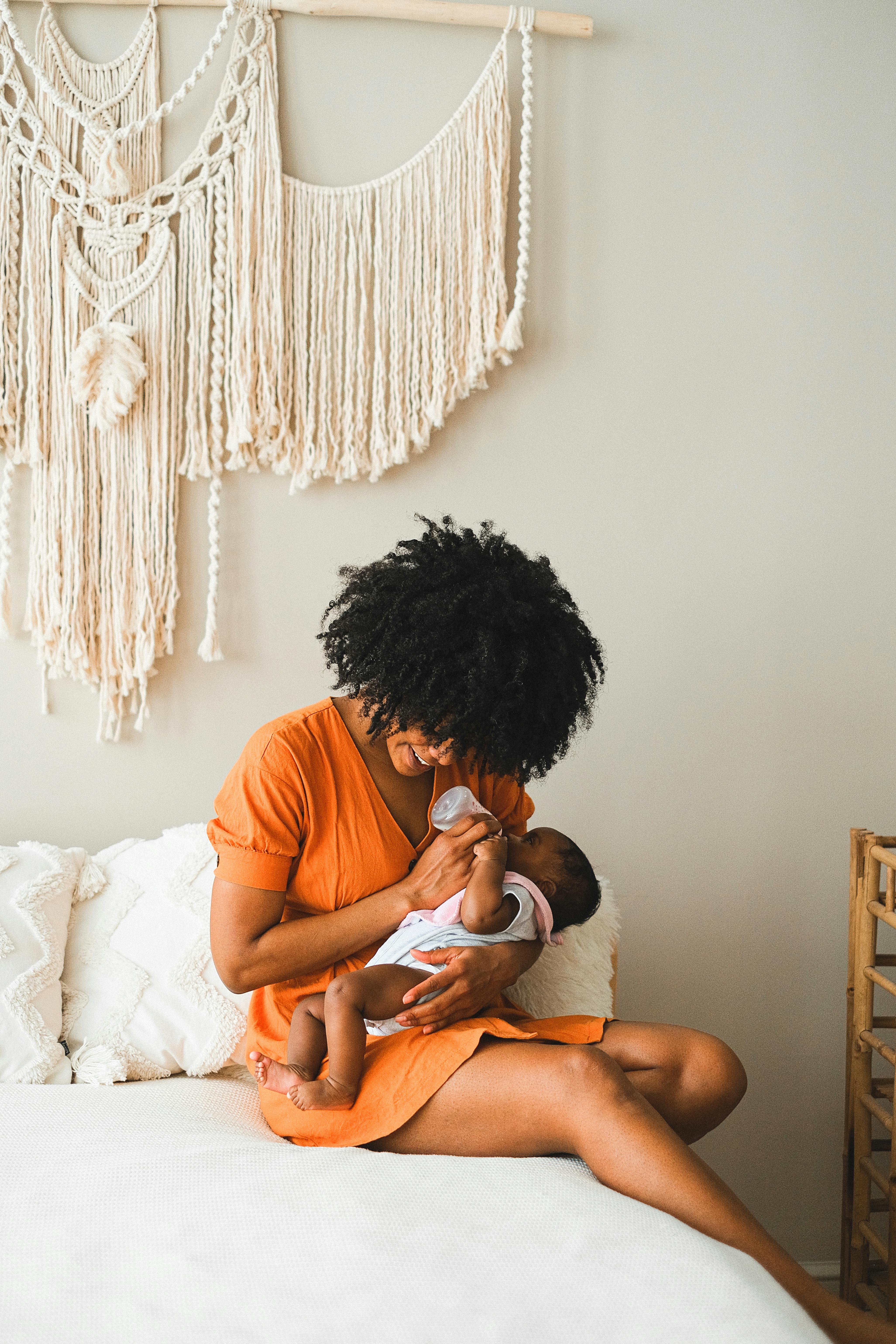 woman sitting on bed while feeding a baby