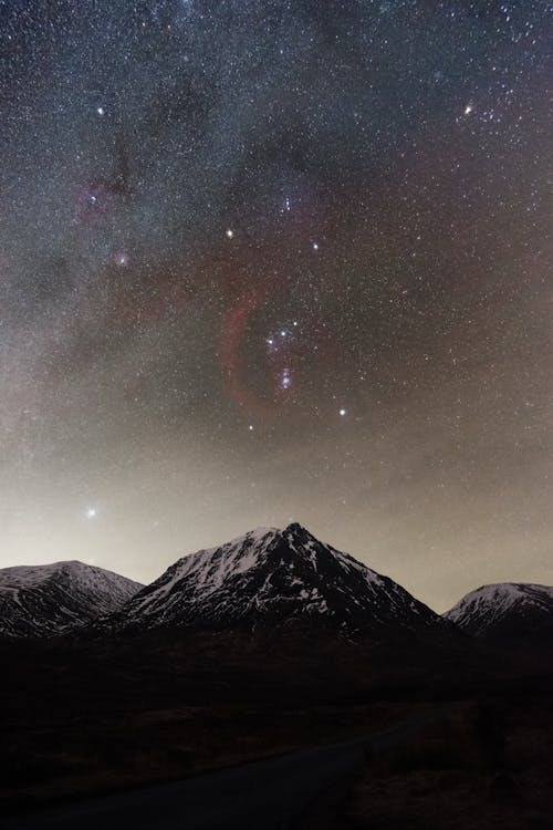 Free Glen Etive astrophotography with the Milky Way and Orion rising above a snowy mountain peak  Stock Photo
