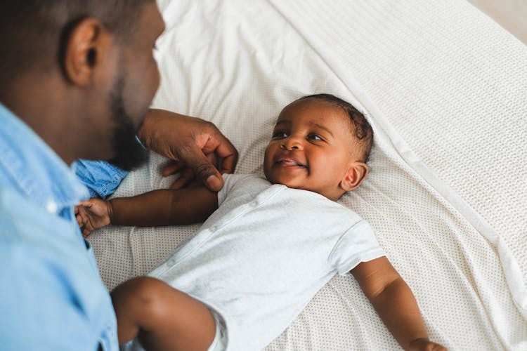 A Man In Blue Long Sleeves Playing With His Baby