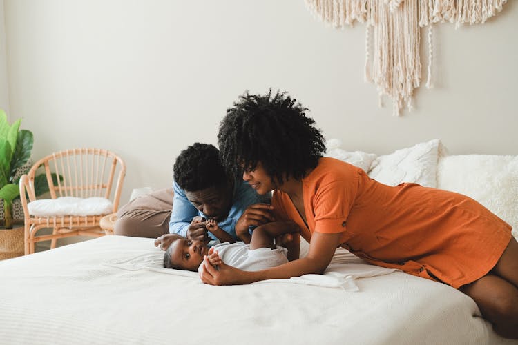 Man And Woman Taking Care Of A Baby On Bed