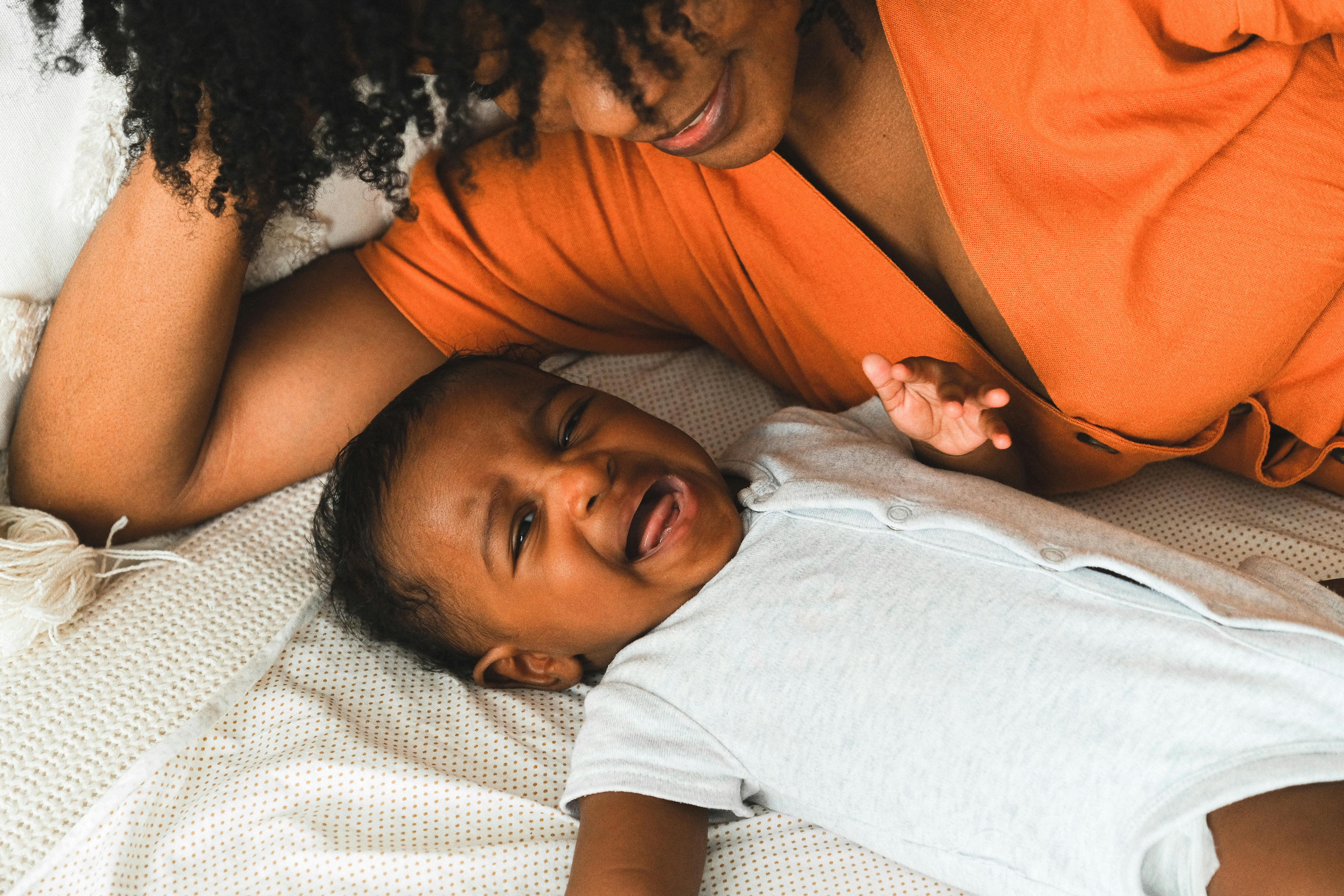 a woman in orange top playing with her baby